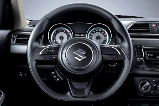 Close-up of the 2018 Suzuki Dzire's steering wheel and driver's cockpit.